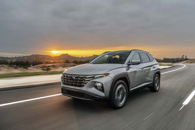 A gray 2023 Hyundai Tucson PHEV drives in the desert at sunset.