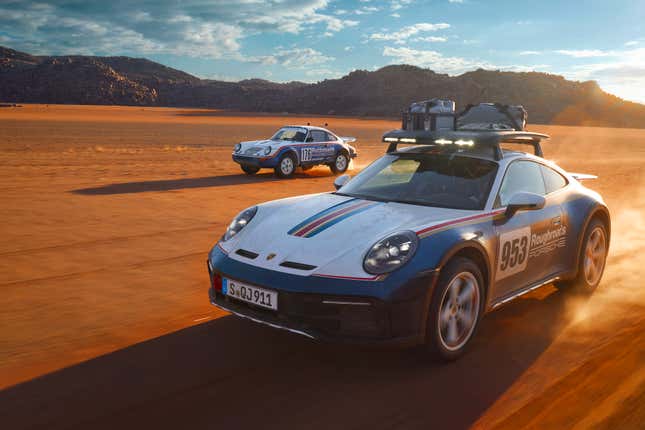 The 2023 Porsche 911 Dakar drives in the desert next to a 1984 Carrera 4WD race car.