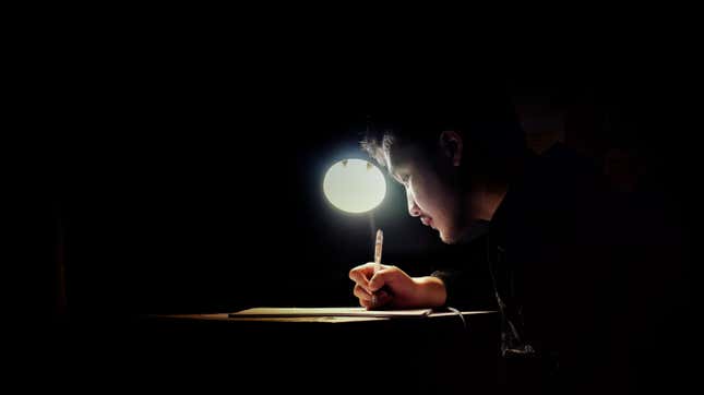 Male student studying under single light source 