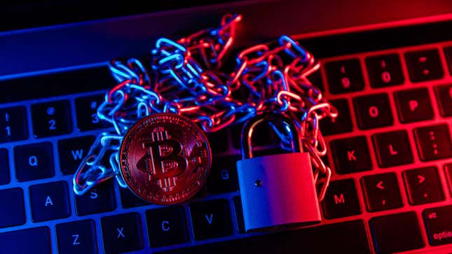 A chain and a padlock sitting on top of a keyboard awash in blue and red light. A gold bitcoin sits on top of the chain.