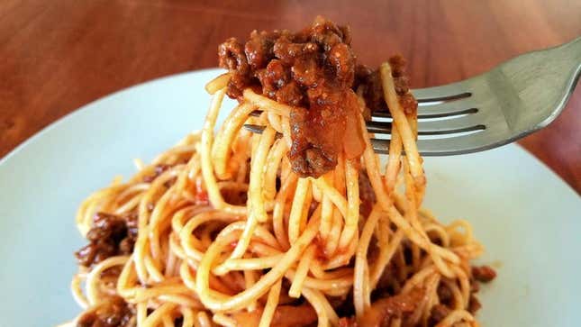 A fork lifting spaghetti bolognese, aka spag bol, from a bowl