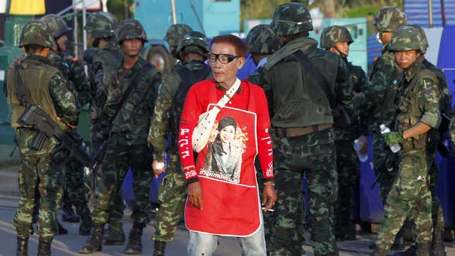 A member of the pro-government “red shirt” group walks past Thai soldiers at an encampment in Nakhon Pathom province on the outskirts of Bangkok.