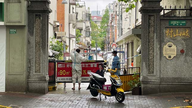A courier in a protective suit makes deliveries to a residential compound amid the pandemic.
