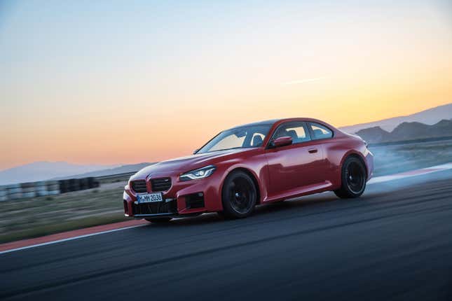 A red BMW M2 burns rubber on a race track.