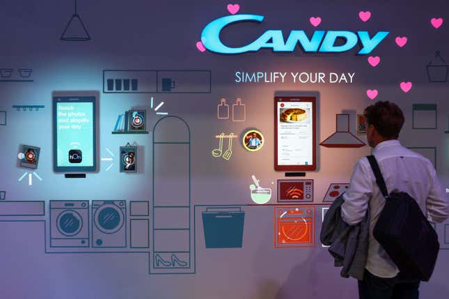 A man stands in front of a smart home display at a consumer technology fair. Above him reads a sign that says "Candy, simplify your day."