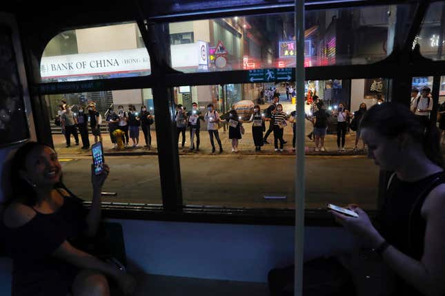 Demonstrators, seen from inside a tram, link hands along a street in Hong Kong.