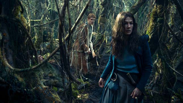 A young man and a woman in a blue cloak move through a dense forest