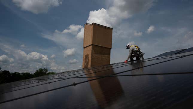 A worker installs solar panels on a roof.