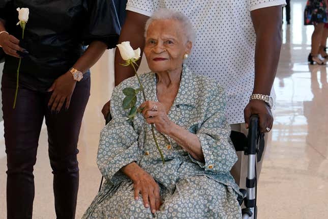 Viola Fletcher, center, the oldest living survivor of the Tulsa race massacre, holds a rose she received as she arrives for a luncheon honoring survivors Saturday, May 29, 2021, in Tulsa, Okla.