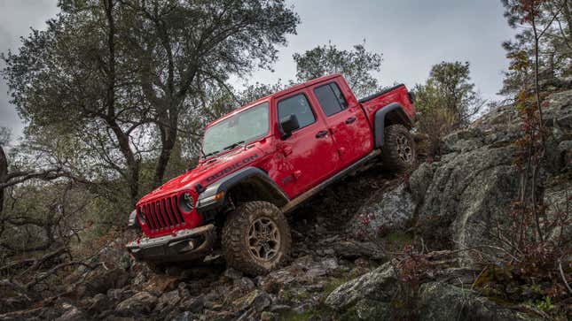 A red Jeep Gladiator pickup driving down a muddy bank 