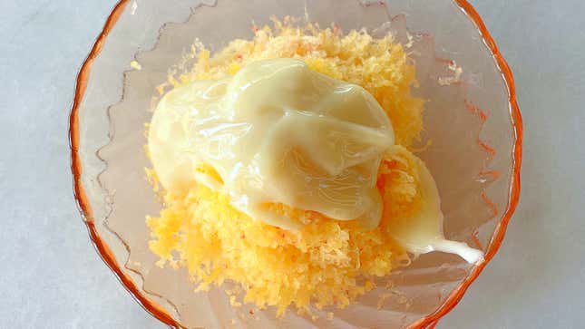 Shaved orange colored fruit with a little bit of condensed milk poured on top
