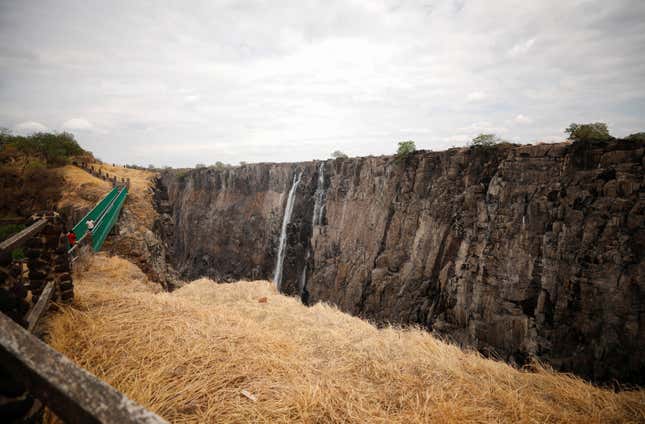 Visitors walk over a bridge as dry cliffs are seen along the parched gorge on the Zambian side of Victoria Falls, Zambia, following a prolonged drought, Dec. 5, 2019.