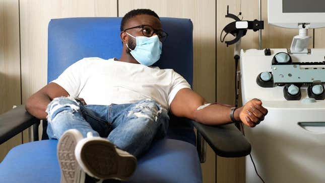 Blood donor wearing mask in hospital chair with tube in arm