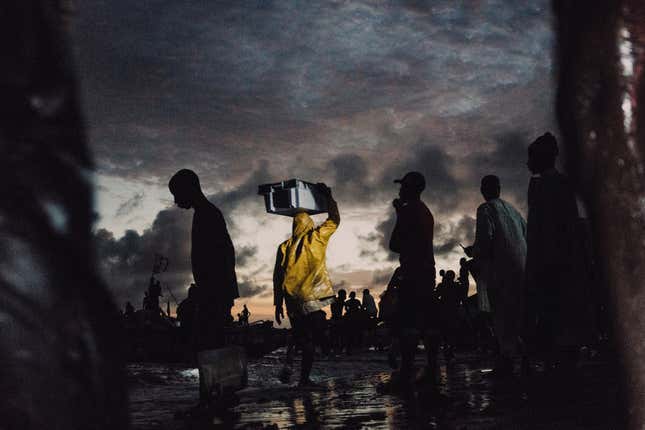 Artisanal fishermen sell their wares in Joal Fadiouth, Senegal, as night falls.