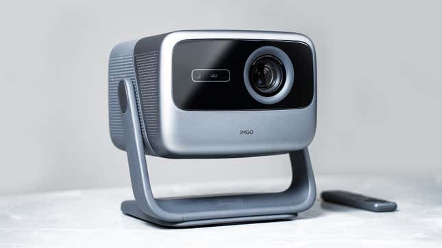 The JMGO N1 Ultra 4K projector sitting on a marble table with a small wireless remote next to it.