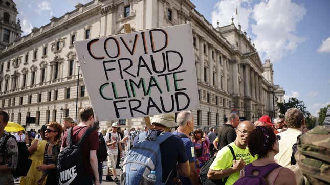 Anti-vaccination protesters, including one with a placard that reads "Covid fraud, climate fraud", gather in Parliament Square in the road outside the Houses of Parliament in central London on July 19, 2021. 