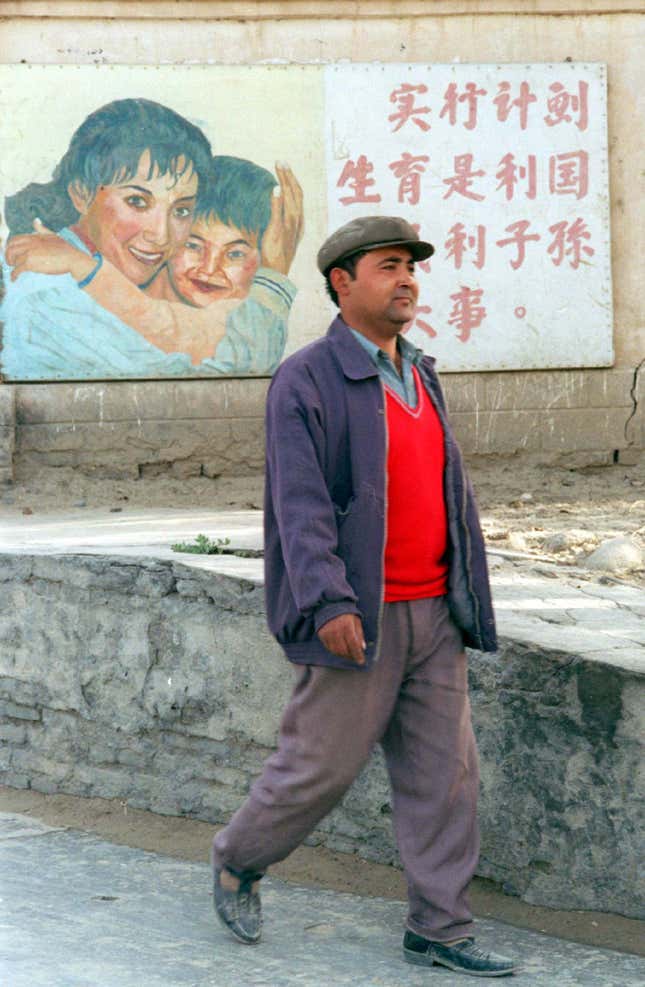 An ethnic Uyghur man walks past a sign that says “implementing family planning is in the interest of the country, people, and posterity” on the outskirts of Khotan in Xinjiang province.