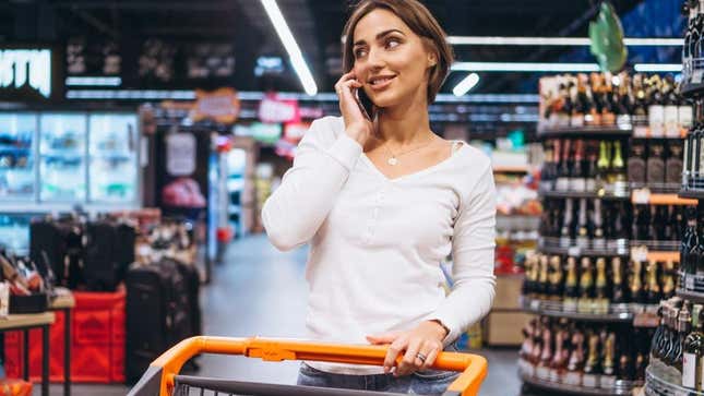 Woman with grocery cart in store talking on cell phone