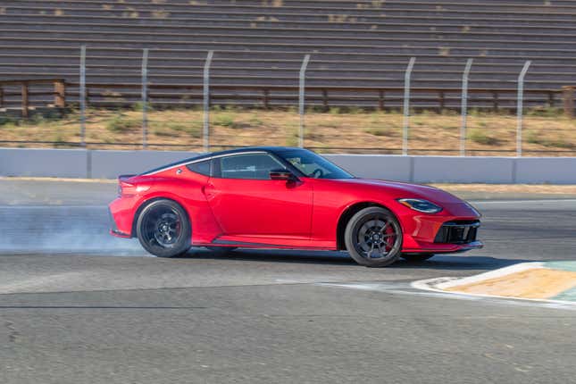 A red 2024 Nissan Z Nismo is sliding on a race track and there is smoke coming from its rear tires