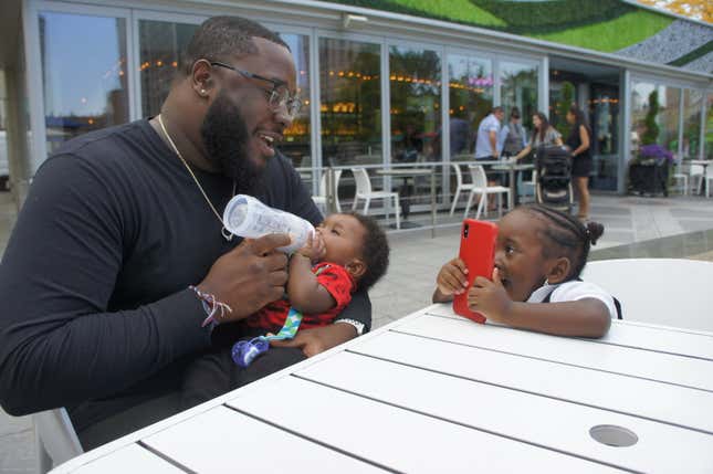 Kamal Muhammad feeds his son Zakai, while his daughter Zala talks to her mother on the phone in October of 2018. Ra is calling from prison.