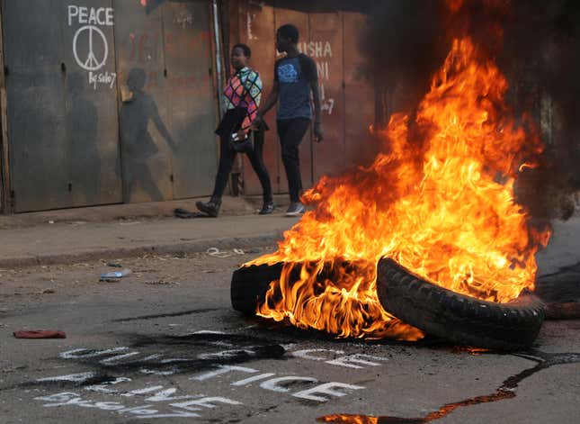 People walk near flaming tyre barricade in Kibera slum in Nairobi, Kenya, August 9, 2017.