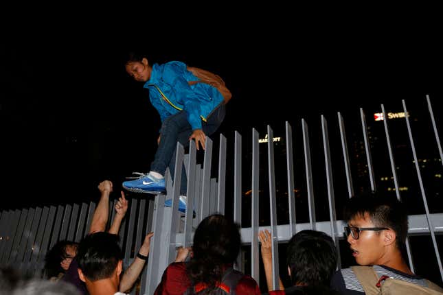 A protester climbs over a fence as she leaves after hundreds stormed into a restricted area at the government headquarters, after a rally ahead of the October 1 "Occupy Central" civil disobedience movement in Hong Kong September 26, 2014.