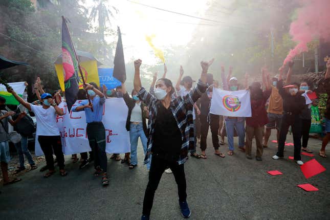 Demonstrators make the defiant three-finger salute and hold flares as they march during a protest against the military coup in Yangon, Myanmar in March.