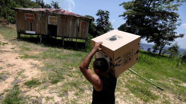 An electoral worker carries an electronic ballot box to a house close to the Amazon River.