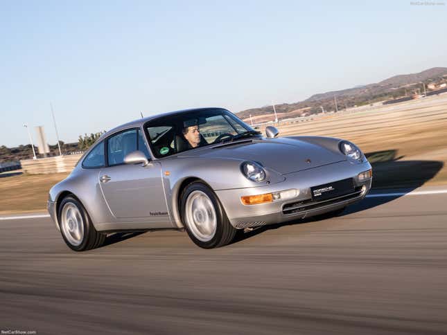 A silver Porsche 993 generation 911 is driving on track.