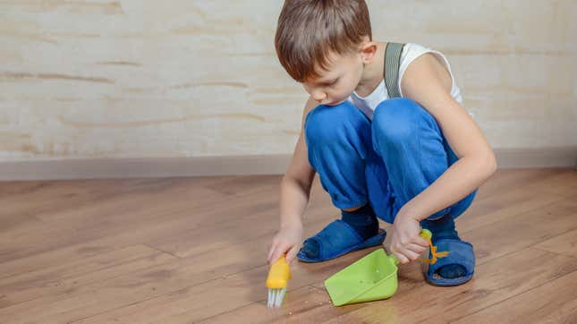 little boy sweeping up floor with miniature broom and dust pan