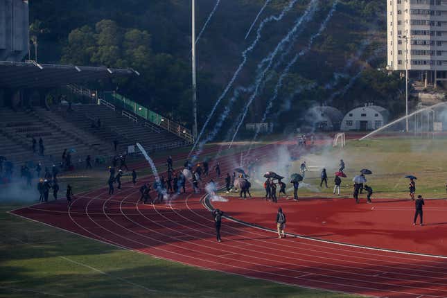 Students try to clear tear gas canisters fired by police on the sports ground.