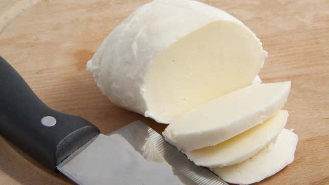 mozzarella cheese being sliced on cutting board