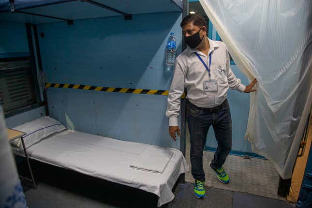 An employee of Indian Railways inspects the converting of a train coach into an isolation ward.