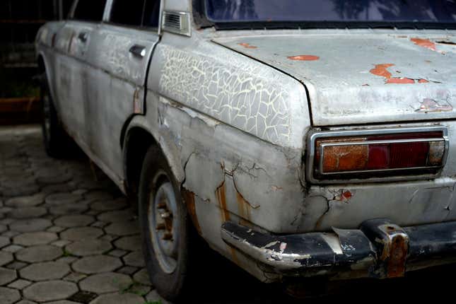 The rear of a rusty, dilapidated Datsun 510.