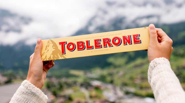 A person holds up a Toblerone chocolate bar. Toblerone will be removing the iconic Swiss mountains from its logo.
