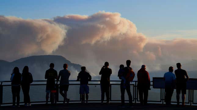 People view smoke from scattered bush fires on a lookout platform in the Blue Mountains.