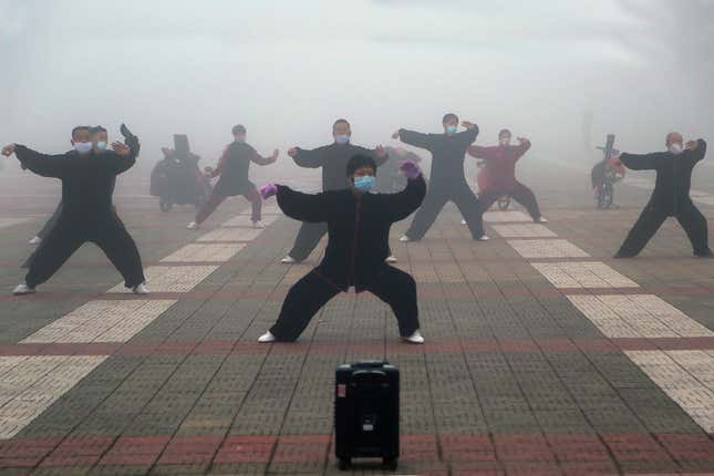 People in face masks pratice tai chi