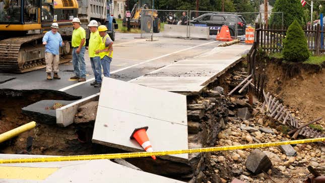Public works officials examine the damage to a road and front yard that was washed away by recent flooding on September 13, 2023, in Leominster, Massachusetts.