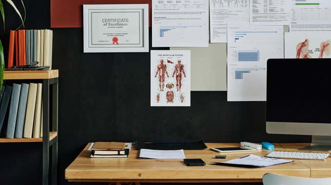view of a doctor's desk or work area with a "certificate of excellence" on the wall