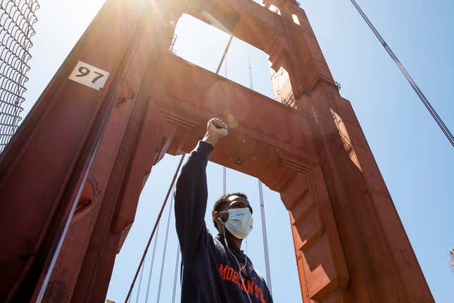SAN FRANCISCO, CA - JUNE 6: A demonstrator raises his fist in the air while sporting a mask as he makes his way with thousands of others across the Golden Gate Bridge in San Francisco, Calif. Saturday, June 6, 2020