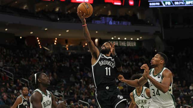 Kyrie Irving of the Brooklyn Nets is defended by Giannis Antetokounmpo of the Milwaukee Bucks during a preseason game at Fiserv Forum on October 12, 2022 in Milwaukee, Wisconsin.
