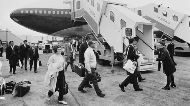 A black and white photo of passengers boarding the first BOAC 747 jumbo jet used for a commercial flight