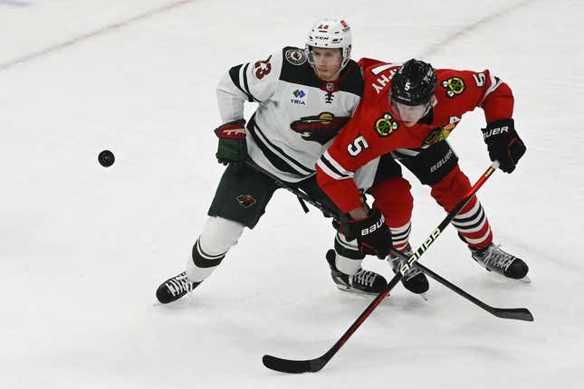 Apr 10, 2023; Chicago, Illinois, USA;  Minnesota Wild center Marco Rossi (23) and Chicago Blackhawks defenseman Connor Murphy (5) watch the puck during the second period at the United Center.