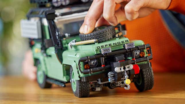 The independent suspension of the Lego Land Rover Defender 90 being demonstrated with someone pressing down on the front of the vehicle.