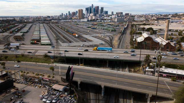 An aerial image from January 16, 2022 shows the Los Angeles skyline as a semi-truck carrying an Amazon Prime trailer crosses a bridge over a section of Union Pacific train tracks.