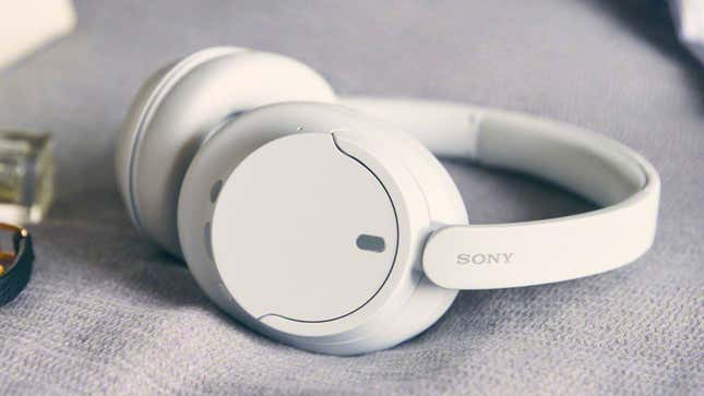 The Sony WH-CH720N Wireless Noise Cancelling Headphones in a white finish sitting on a gray blanket.