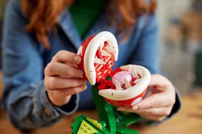 A photo shows a woman opening the jaws of the new Mario-themed Lego plant. 