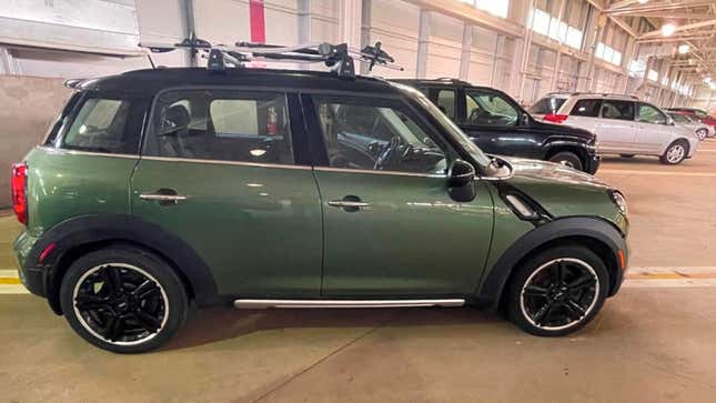 A dark green Mini Countryman SUV with black rims and roof bars 