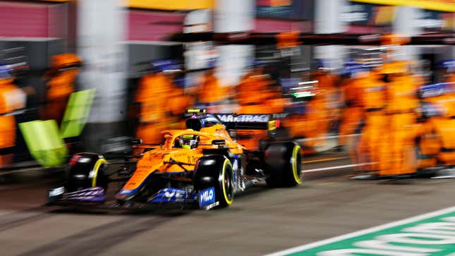 An orange McLaren F1 car stops in the pits.