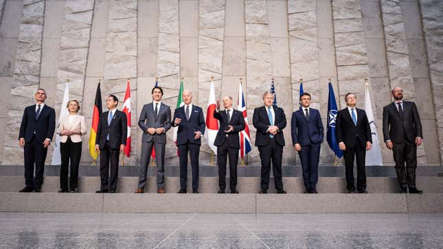 World leaders stand in front of flags.